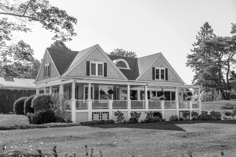 A white two-story house with a wraparound porch